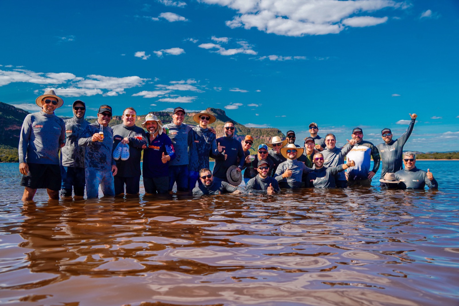 Grande grupo de pescadores celebrando dentro d'água no Lago do Manso