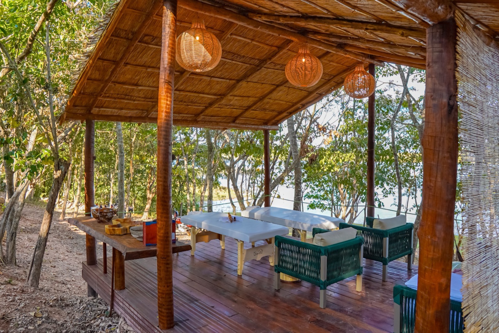 Spa ao ar livre do Manso Fishing Resort com macas de massagem, deck de madeira e luminárias artesanais