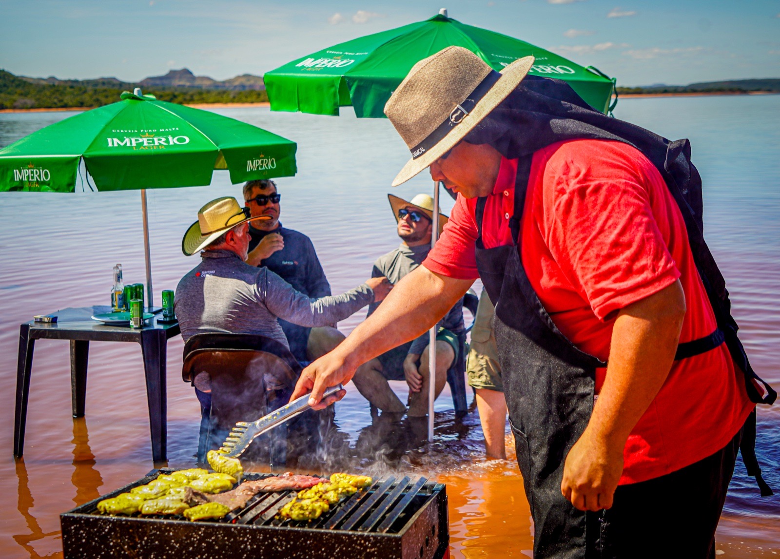 Chef preparando espetinhos na grelha à beira do lago