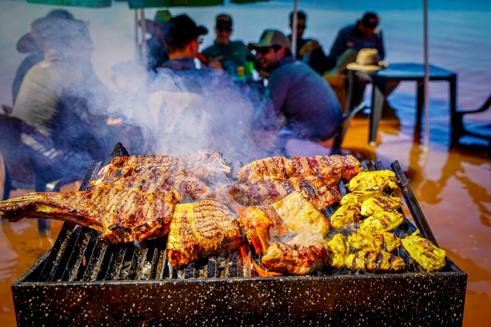 Churrasco na brasa com costelas e cortes nobres à beira do lago
