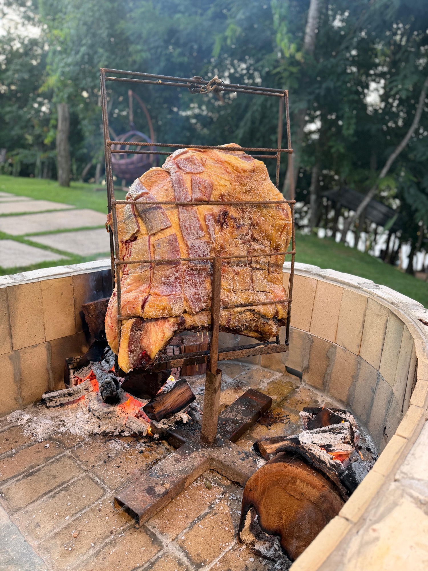 Costela de chão assando na grelha vertical sobre brasas no forno de tijolos do Manso Fishing Resort