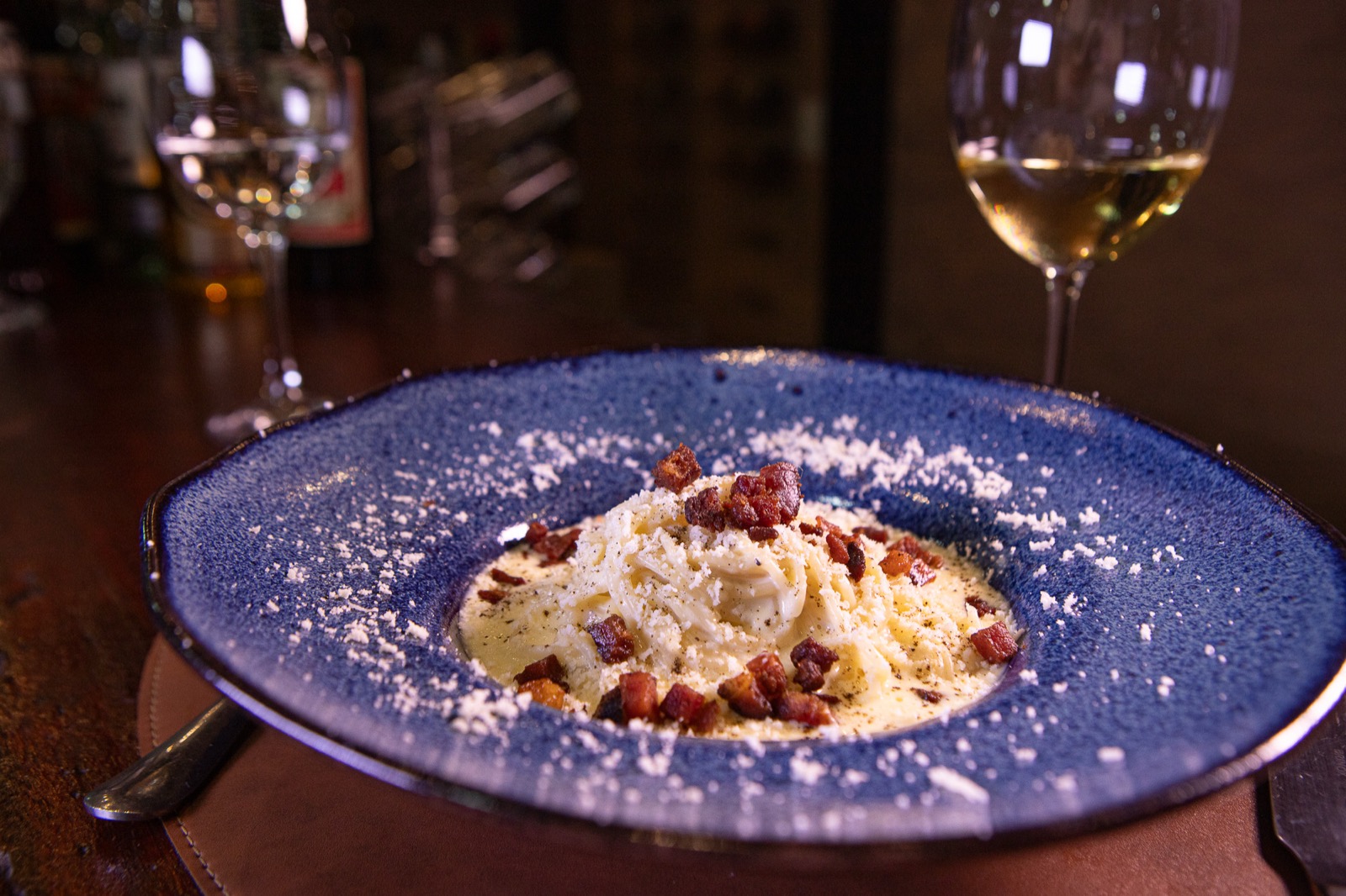 Massa carbonara premium servida em prato artesanal azul