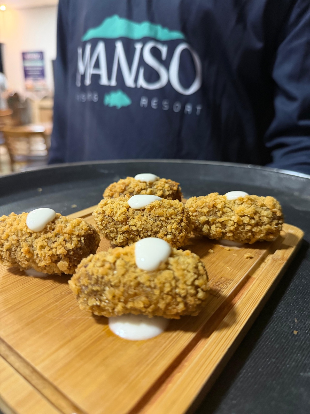 Croquetes dourados servidos na tábua de madeira no Manso Fishing Resort