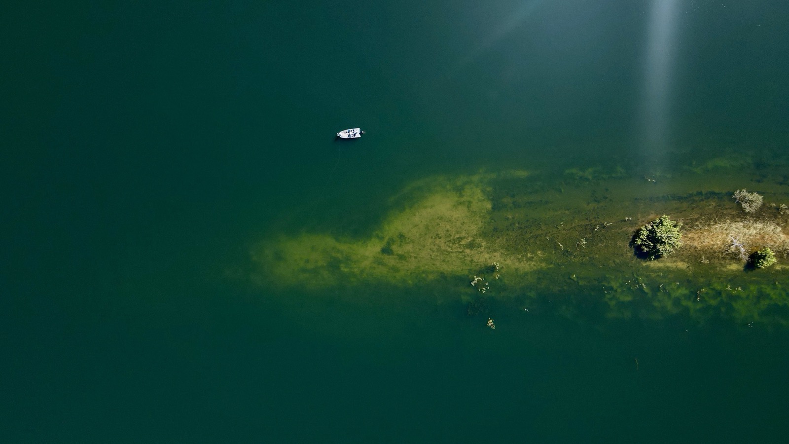Vista aérea de drone mostrando barco solitário nas águas cristalinas verdes do Lago do Manso